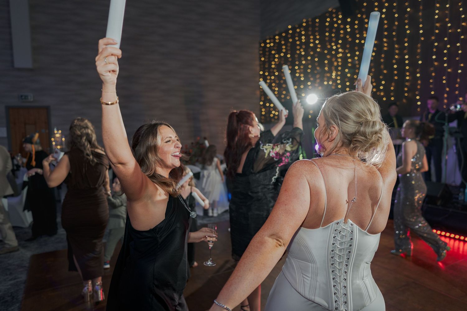 People dancing and celebrating at a wedding reception with string lights glowing in the background at the Sandman Signature, Aberdeen.
