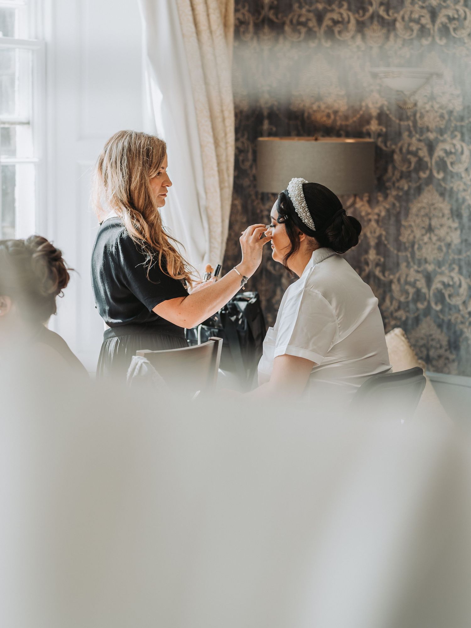 Professional makeup artist applying cosmetics during bridal preparation at Oswald House.