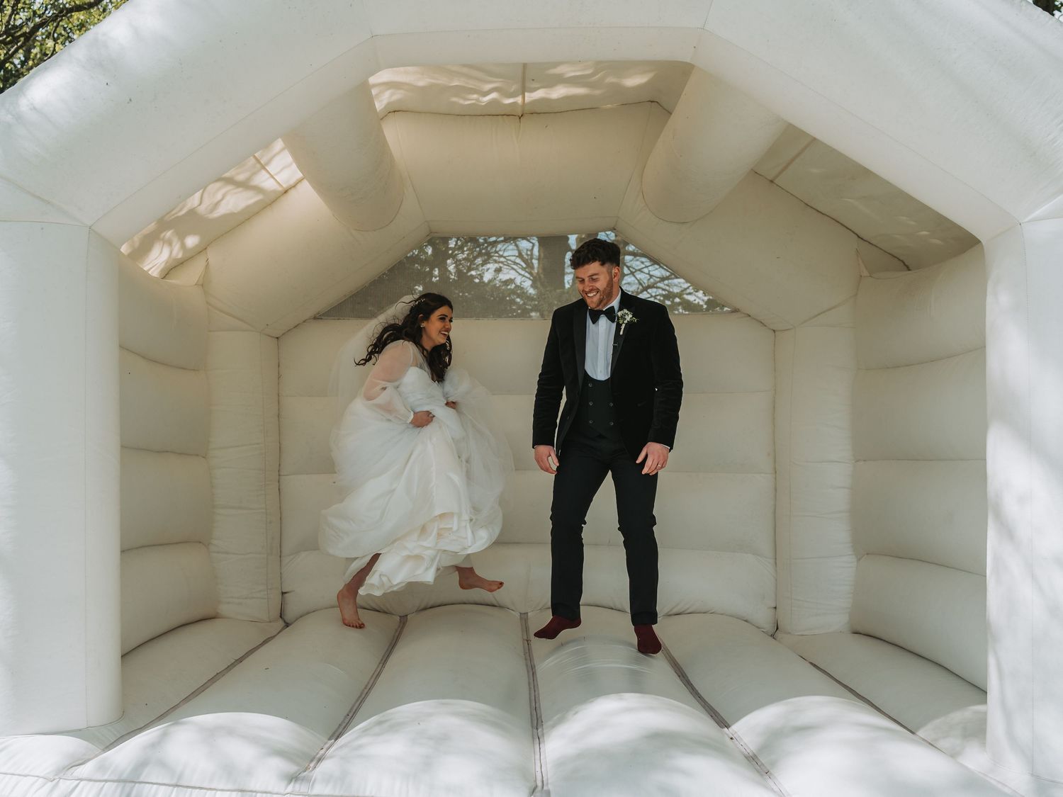 Newlyweds jump and play together inside an all-white wedding bounce house.