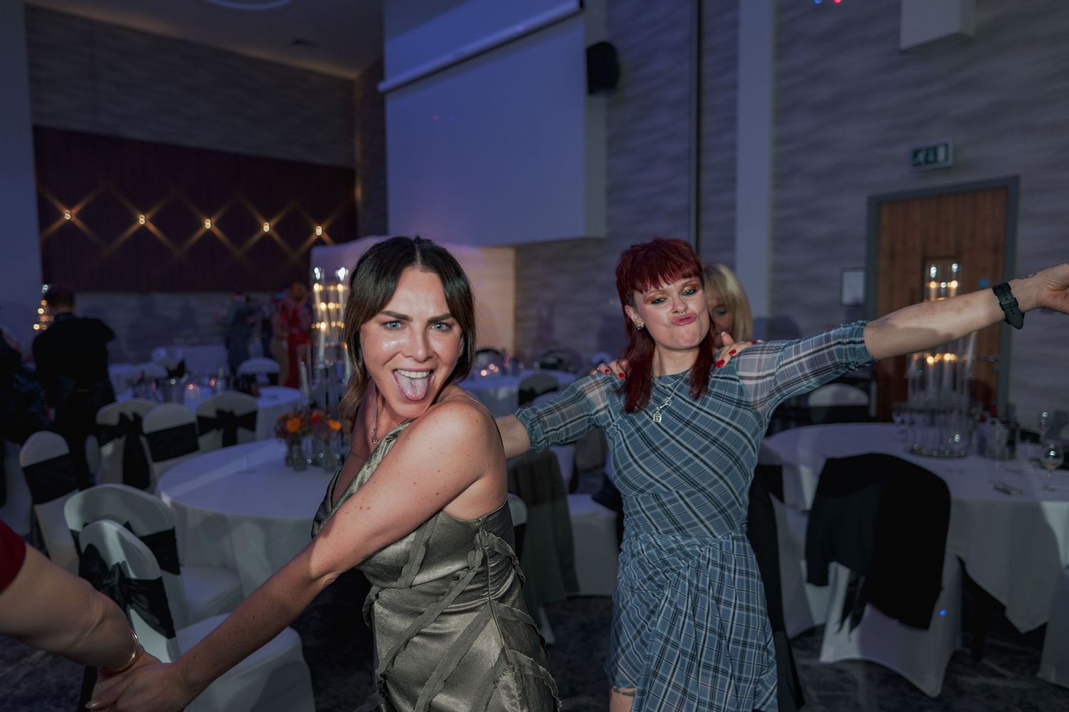 Guests dancing and celebrating at an indoor event with string lights and blue ambient lighting.