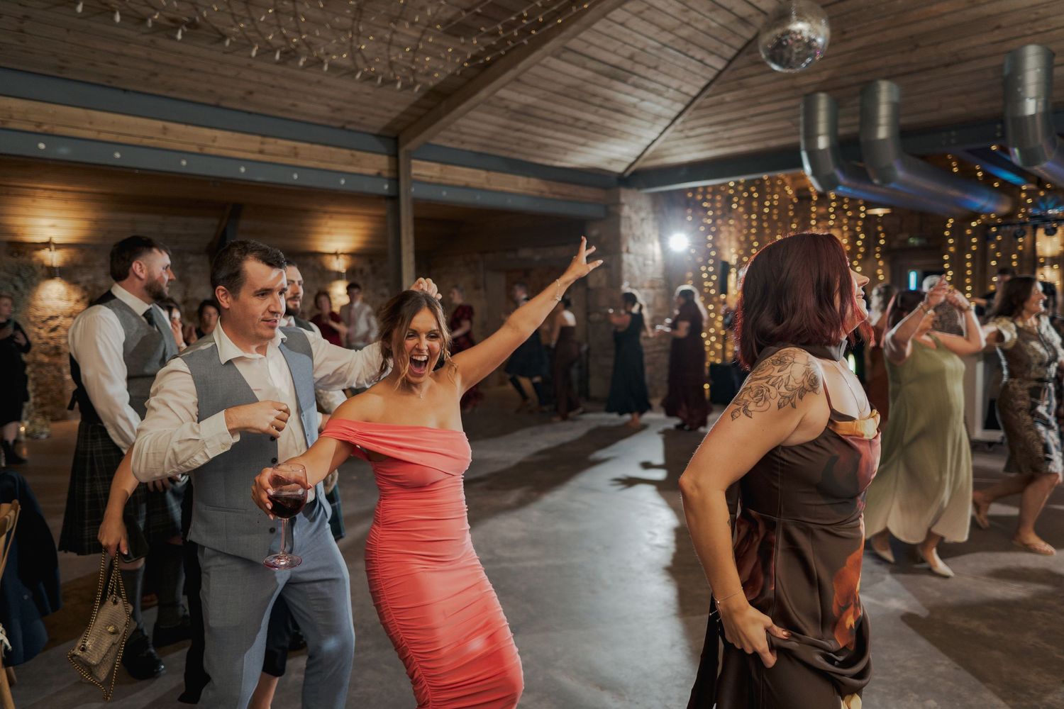 Guests enjoying themselves on the Falside Mill dance floor during a lively wedding celebration.