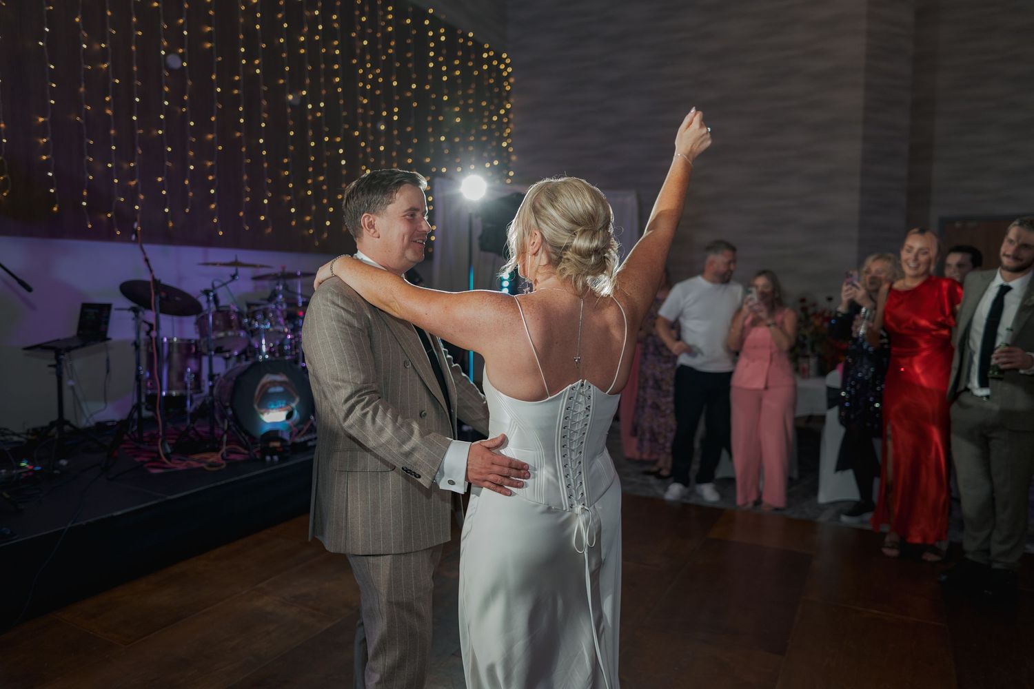 Dancers twirl and move together on a dimly lit dance floor with sparkling lights in the background.