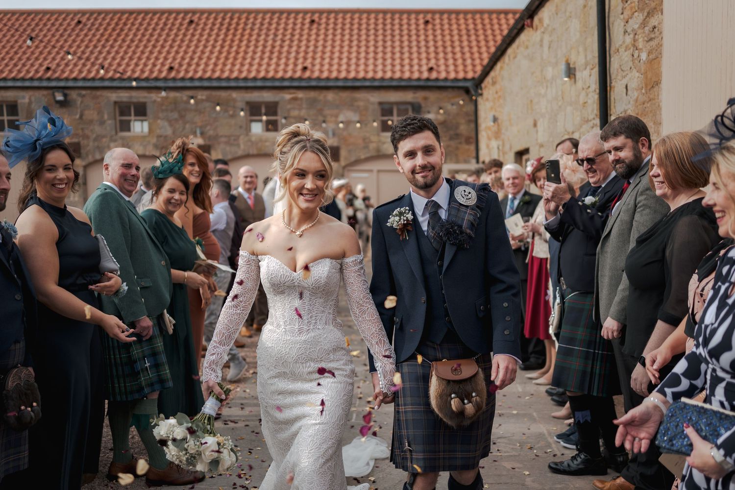 Wedding guests throw confetti over a couple during an outdoor celebration at Falside Mill.
