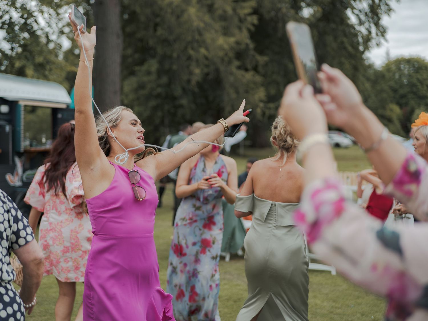 People dance joyfully outdoors in a group wearing colorful summer attire at a community event.