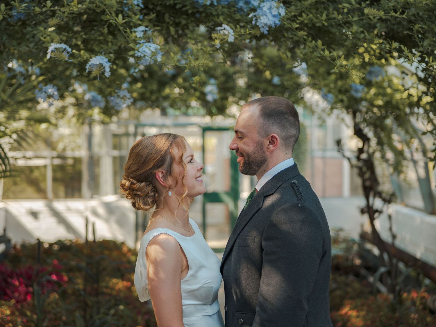 A romantic couple in wedding attire share intimate moments together at David Welsh Winter Gardens.