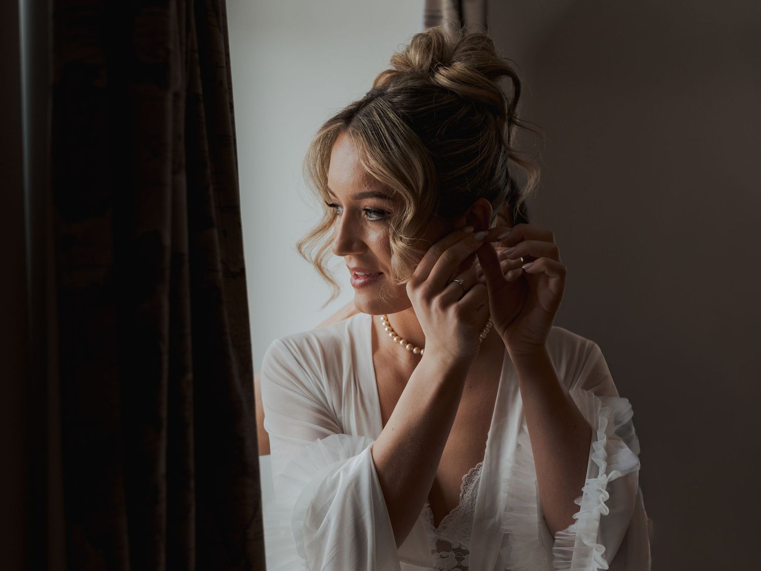 Person in white clothing sitting against dark background covers face with hands in series of emotional poses.