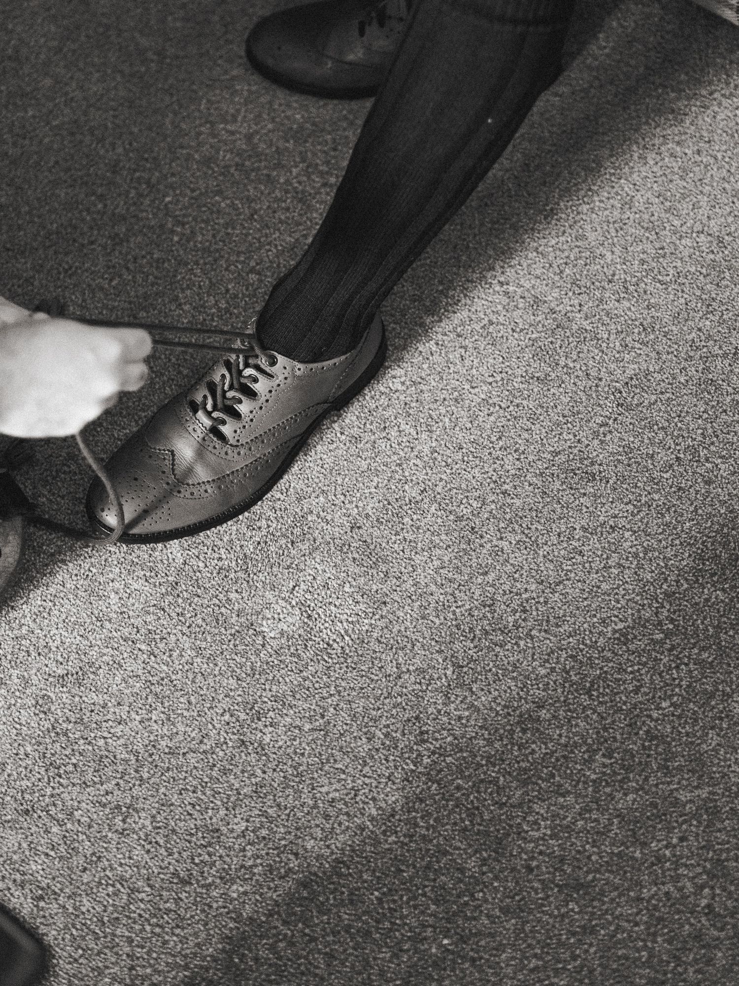 A series of black and white photographs showing close-up details of formal dress shoes on carpet.