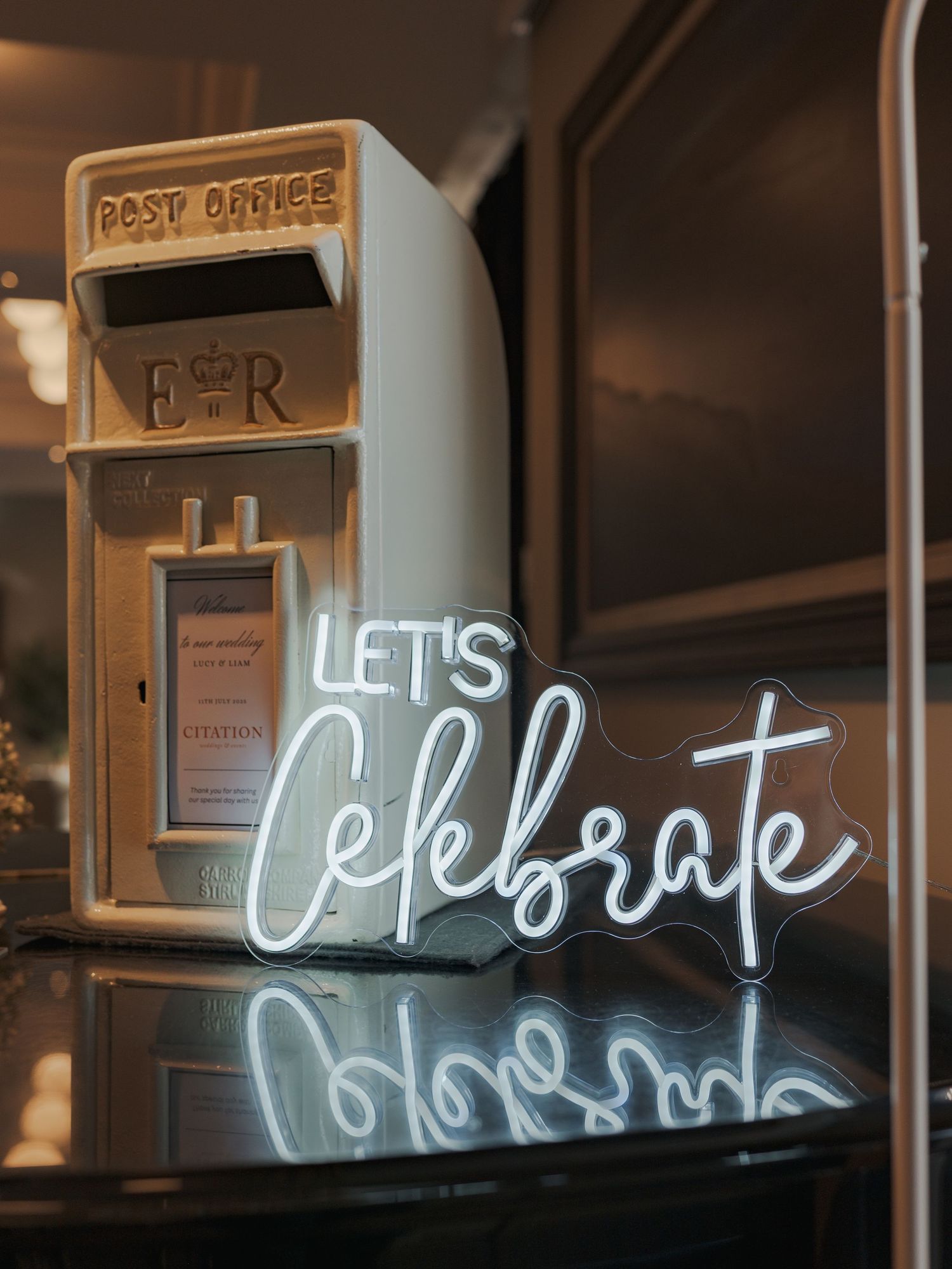 Series of illuminated neon signs spelling celebratory phrases in cursive against a dark background.