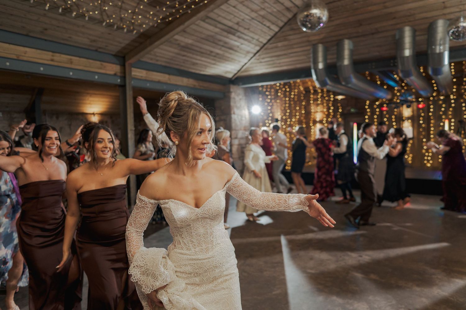 Wedding reception dance party at Falside Mill with disco ball and string lights creating a festive atmosphere.