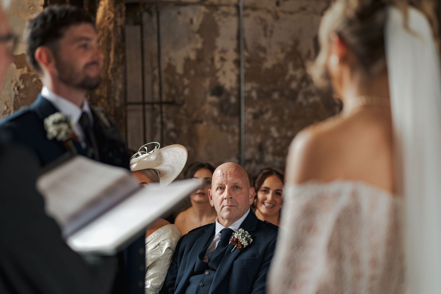 Romantic wedding couple shares intimate moments in a rustic stone venue with warm lighting and elegant decor.
