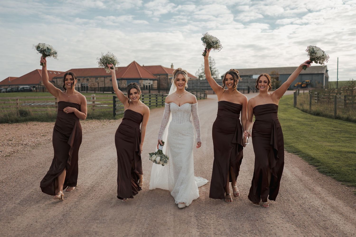 Wedding party walks down a dirt road in brown dresses and white gown creating fun photo sequence at Falside Mill.