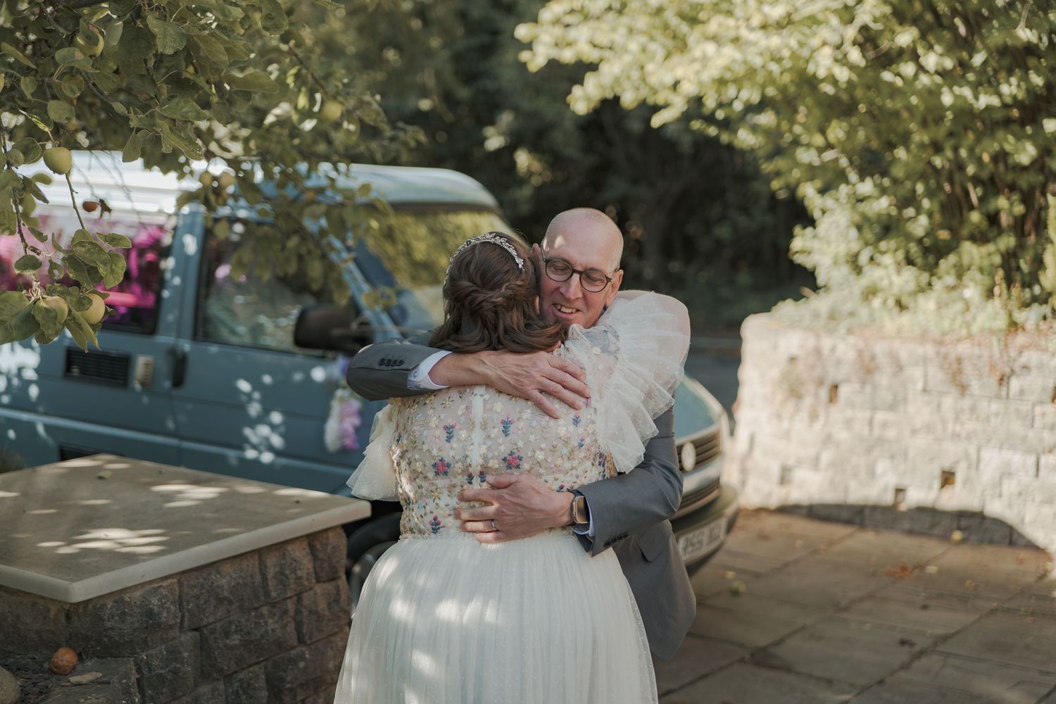 Wedding couple shares an intimate embrace while twirling and dancing outdoors in romantic natural lighting.