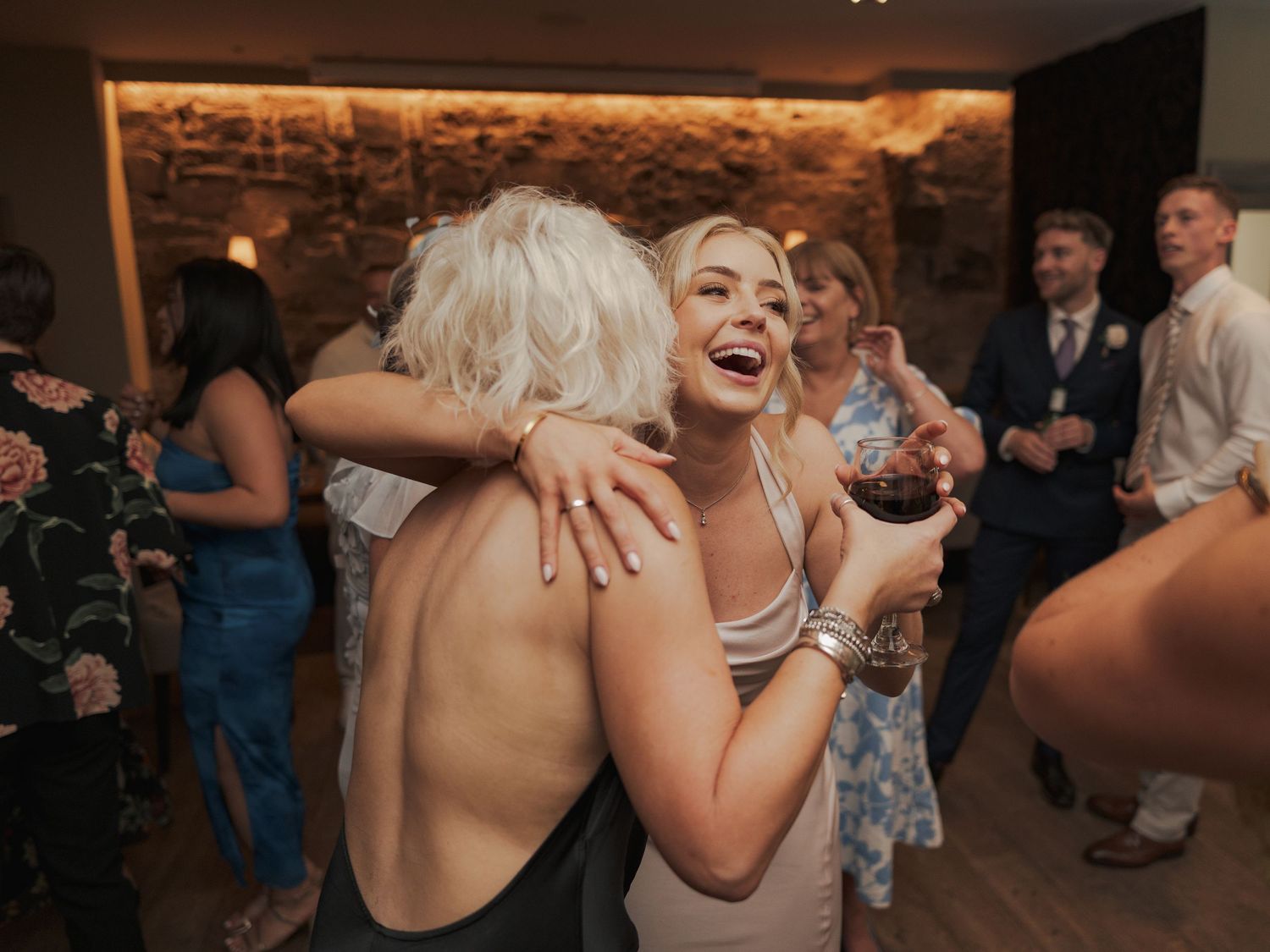 Wedding reception guests dancing and celebrating on a dimly lit dance floor with stone walls at Citation Glasgow.