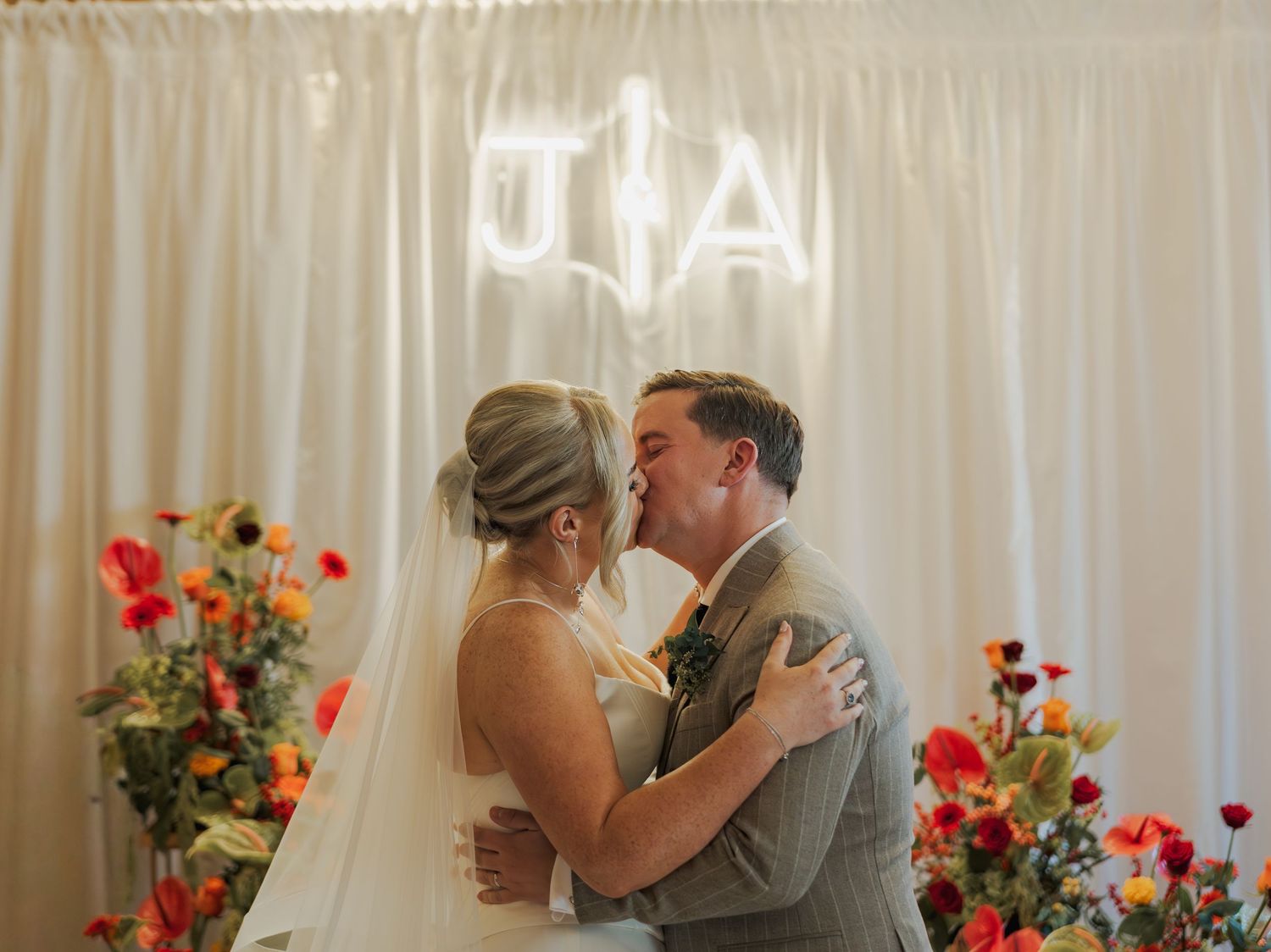 A couple shares a tender moment at their wedding ceremony with floral decorations and white curtains in the background at the Sandman Signa.