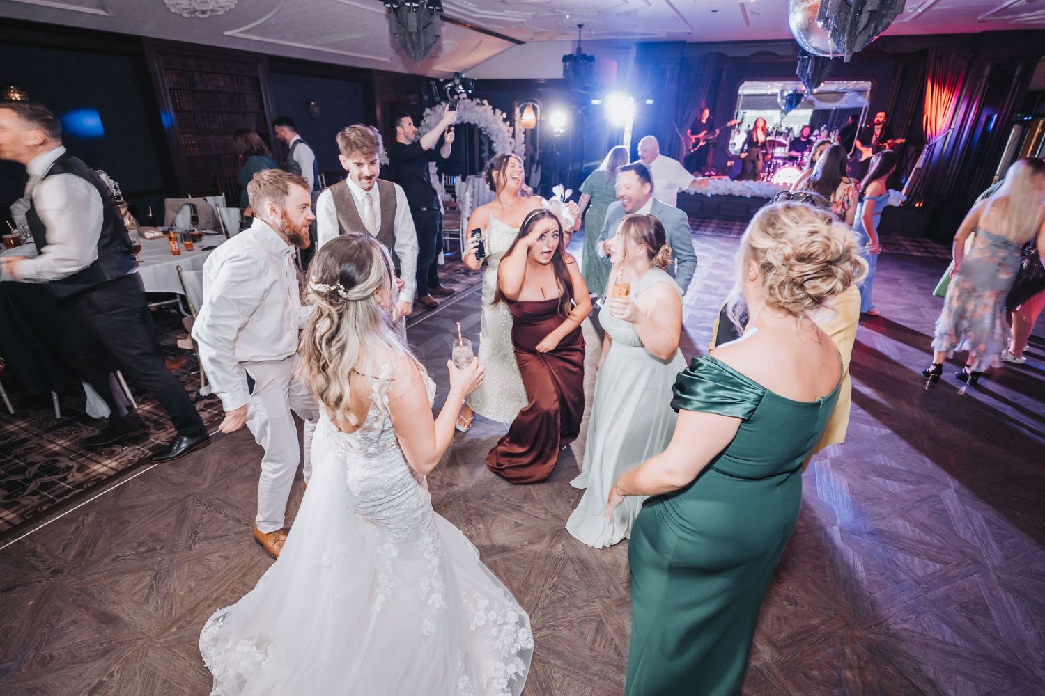 Wedding guests dancing and celebrating on the dance floor at an evening reception with colorful lighting at Cornhill Castle.