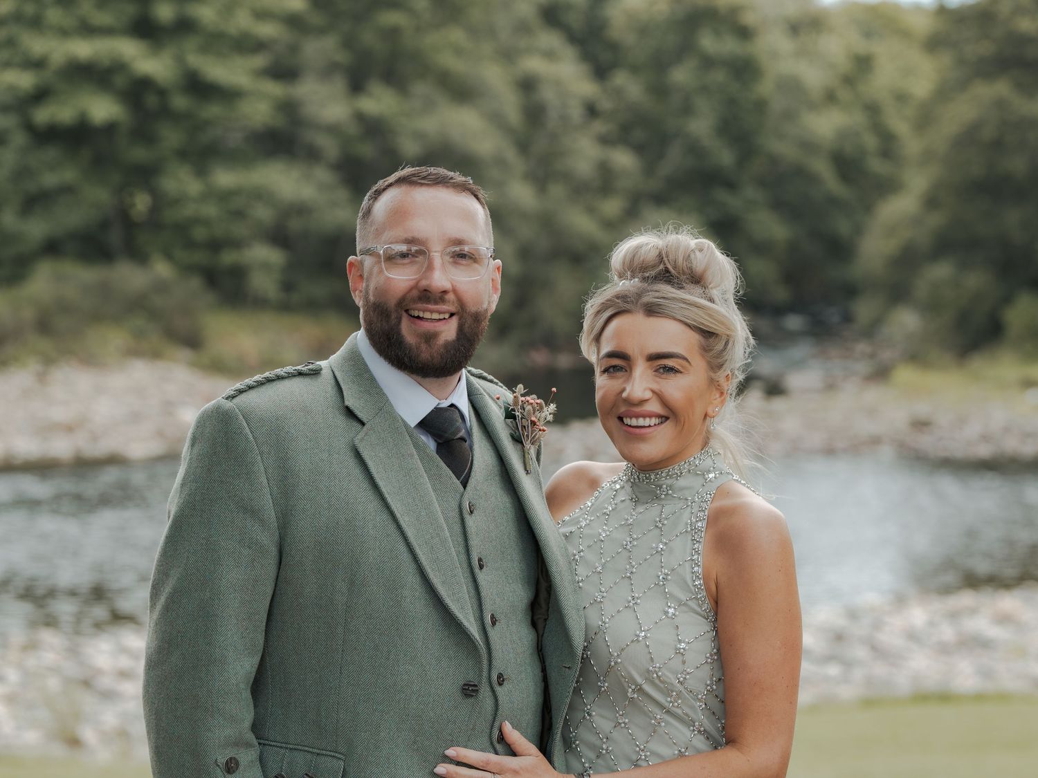 Wedding couple shares a joyful moment together outdoors in matching sage green attire at Banchory Lodge.