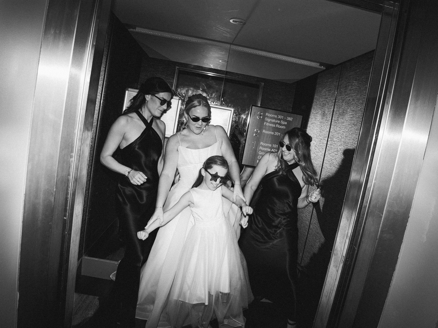 Wedding guests dancing together under warm lighting at an indoor reception venue.