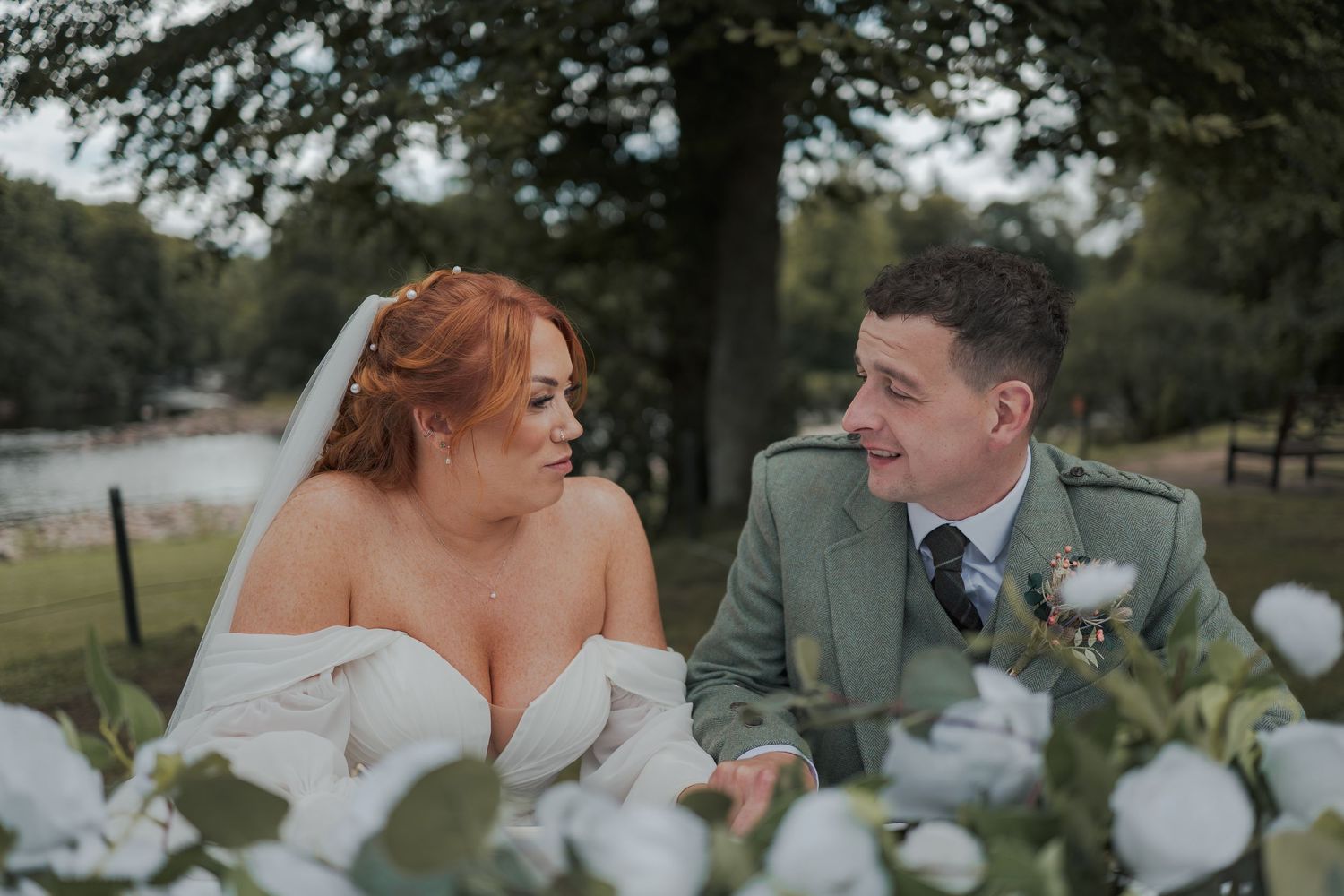 Loving couple share joyful moments during their outdoor wedding celebration surrounded by trees and natural scenery at Banchory Lodge.