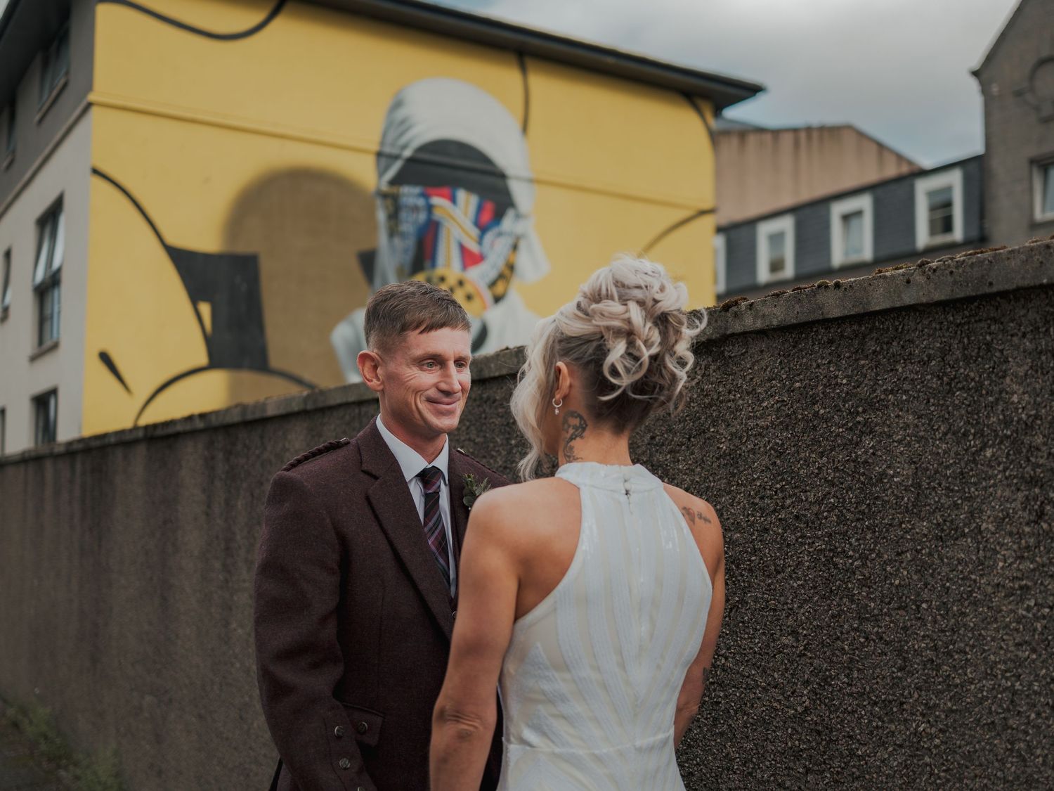 A bride and groom share a romantic moment in front of a colorful street mural on their wedding day.