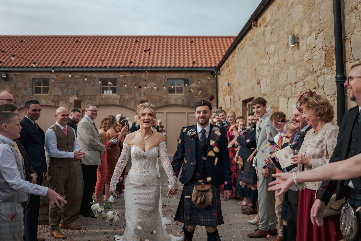 Wedding guests celebrate with confetti outside at Falside Mill.