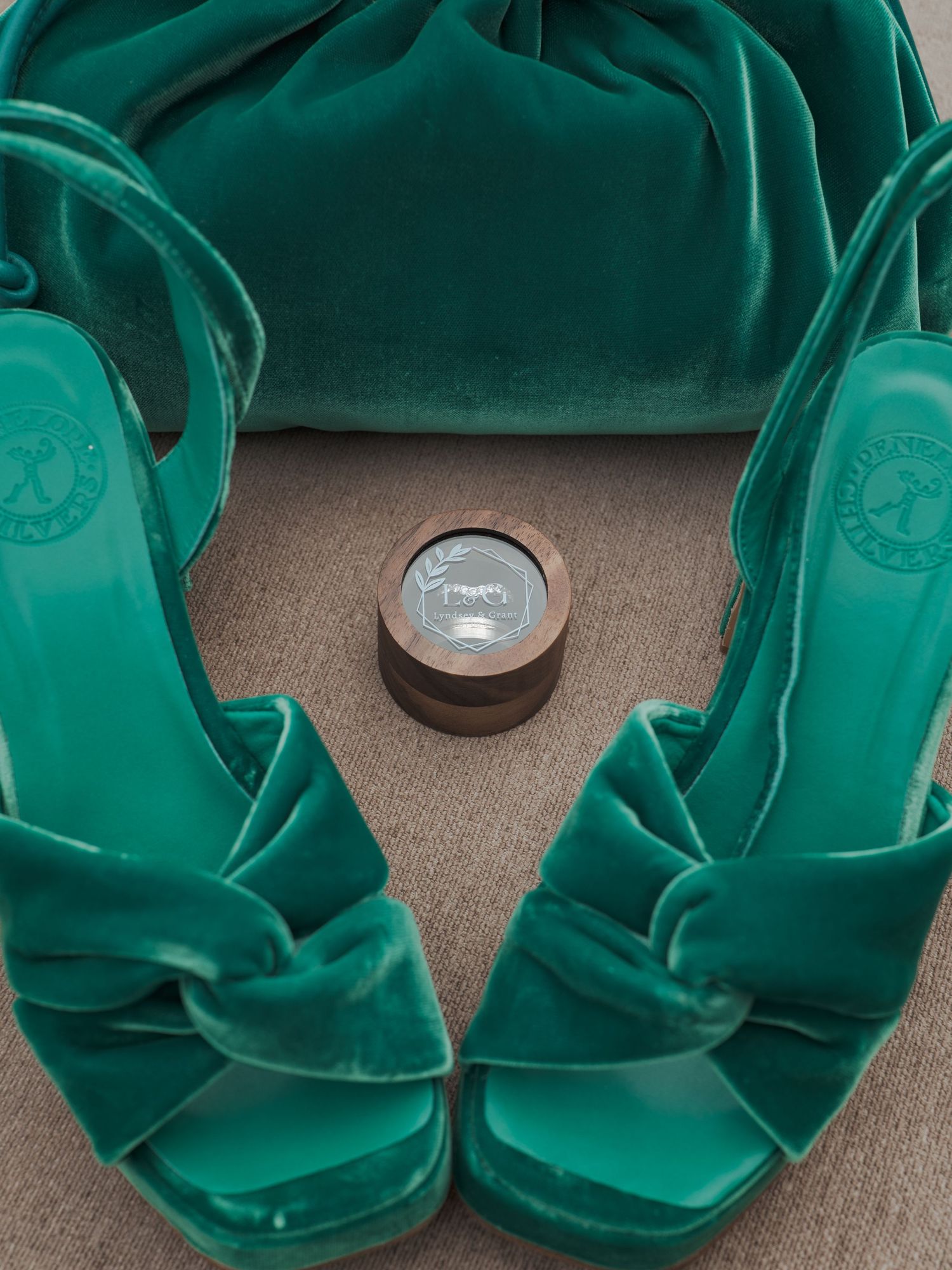 Metallic silver coin placed on teal silk fabric showing circular pattern and texture arrangement.