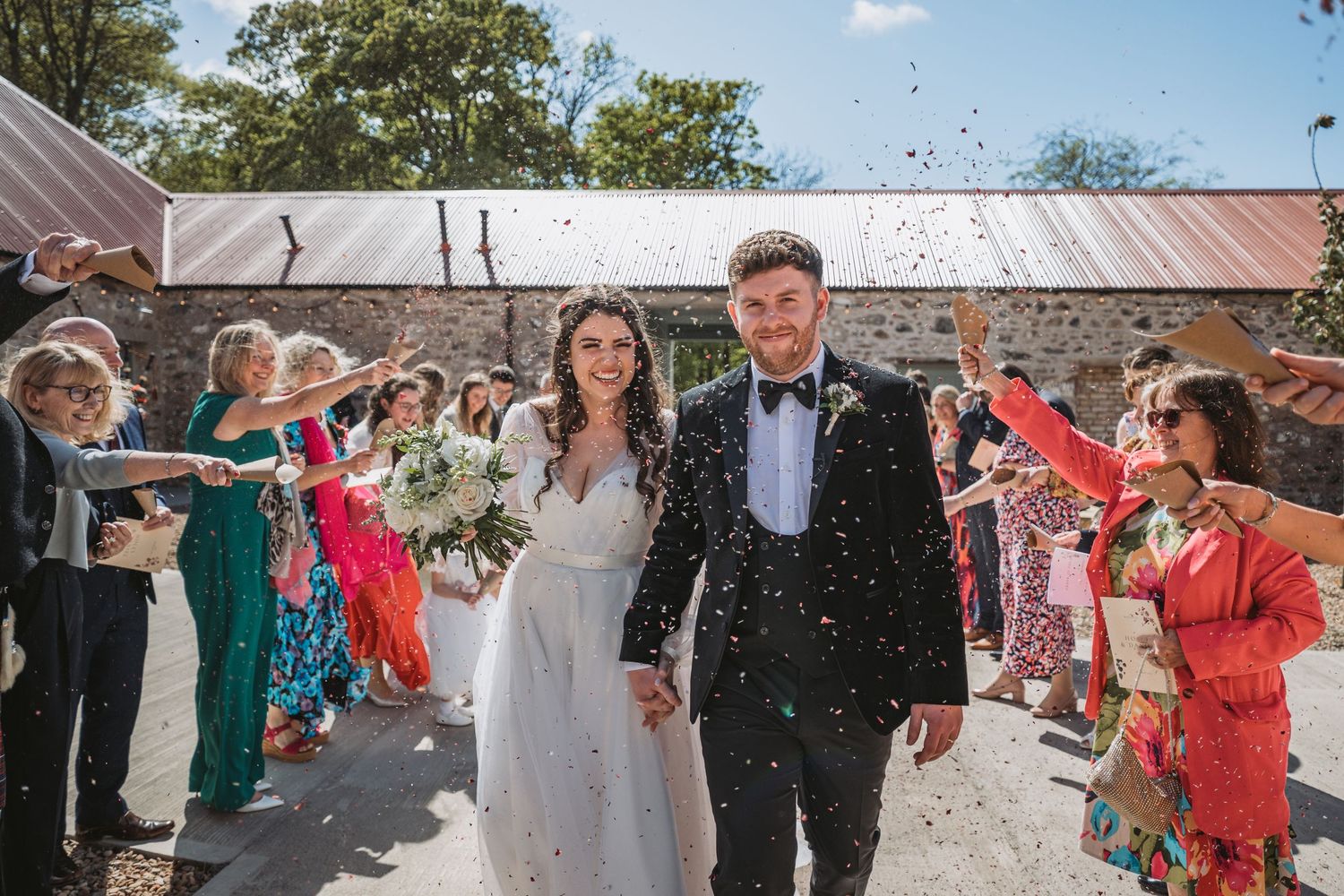Wedding party celebration with guests throwing confetti over couple walking through Kinclune House & Estate.