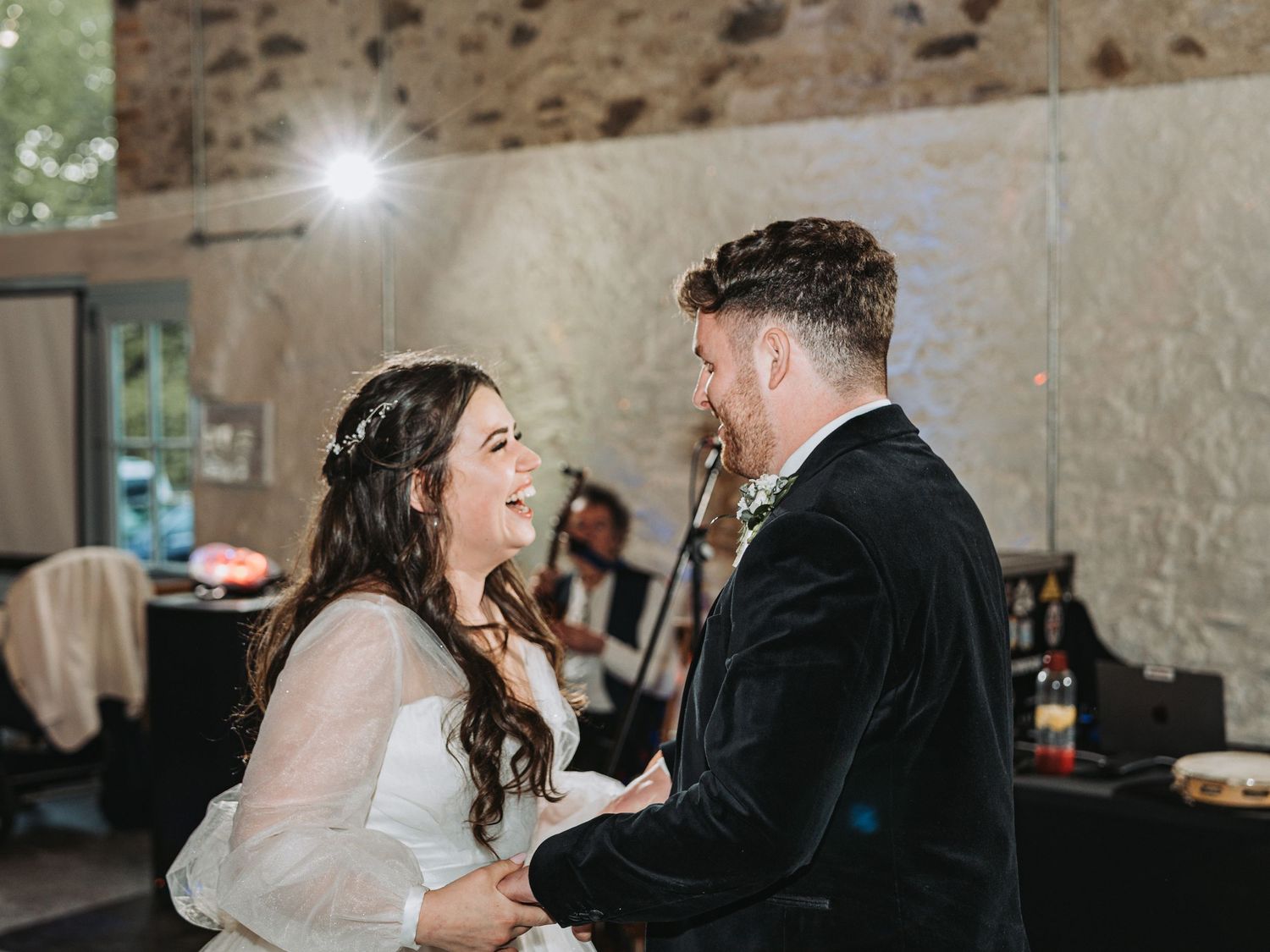 A joyful moment shared between a couple laughing during their first dance at the rustic stone wall Kinclune Steading