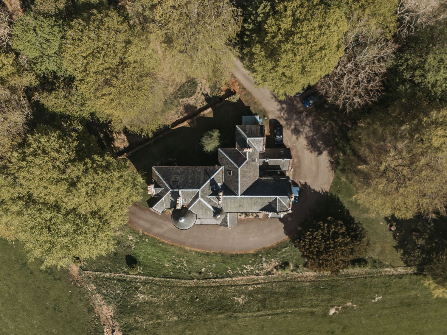 Aerial view of Kinclune House with multiple rooflines surrounded by trees and winding paths.