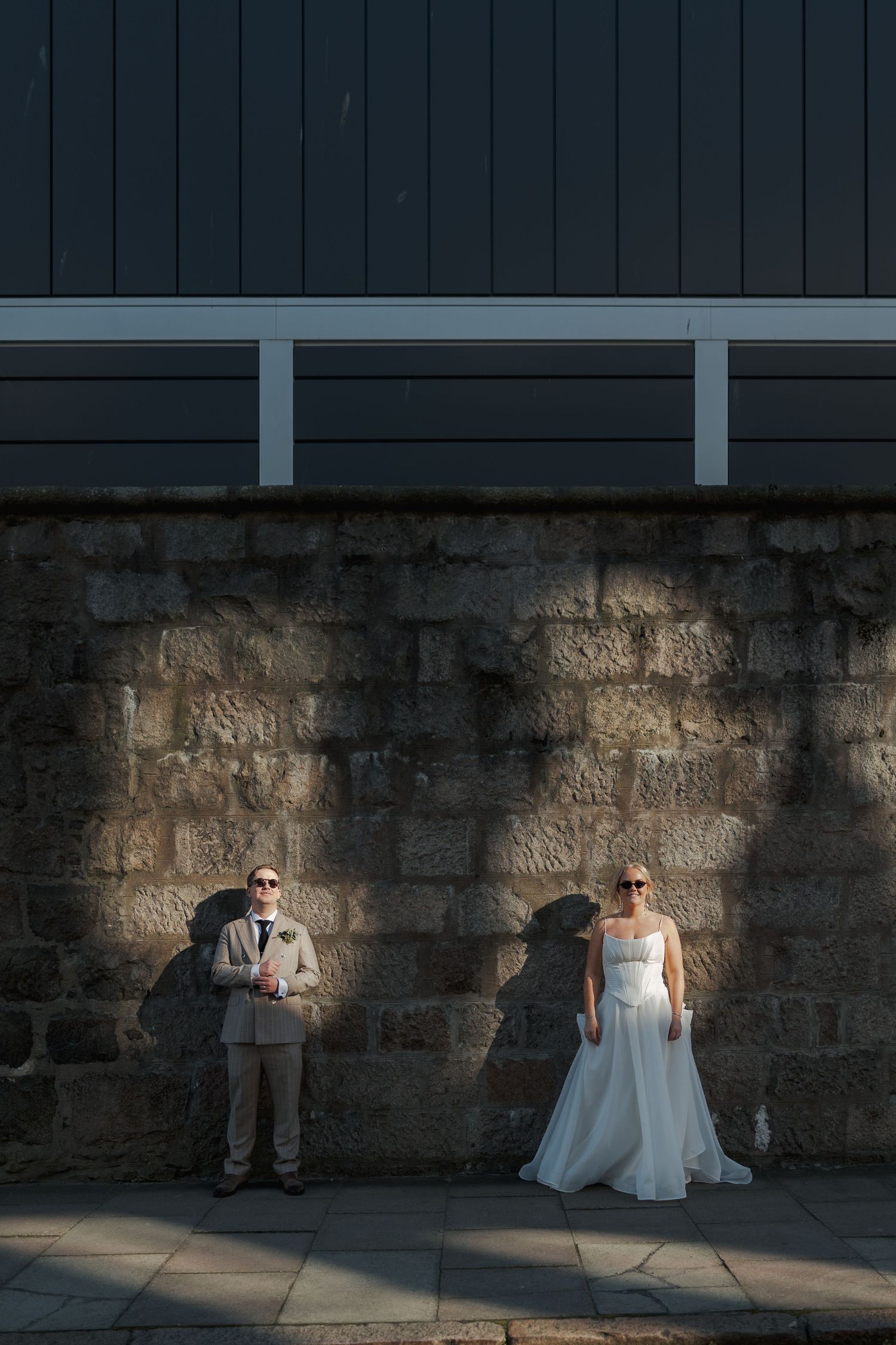 A sequence of photos showing a couple sitting in sunlight against a stone wall during a wedding photo session at the Sandman Signature, Abe.