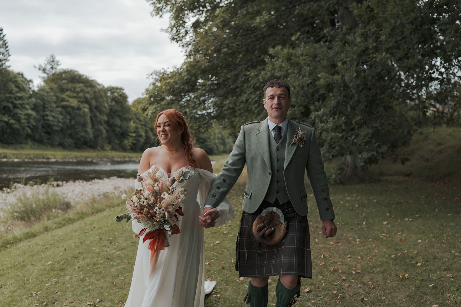 A couple joyfully celebrates their wedding day in an outdoor countryside setting with rustic natural surroundings at Banchory Lodge.