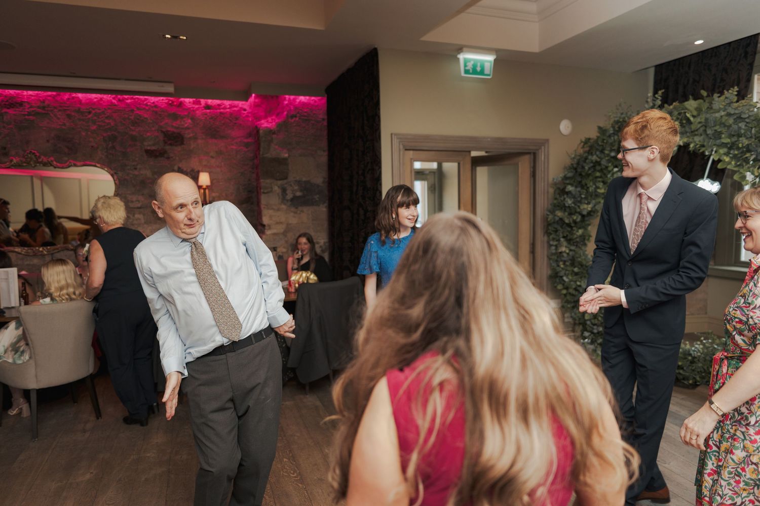 Couples dancing together at a wedding reception with decorative lighting and indoor venue setting.