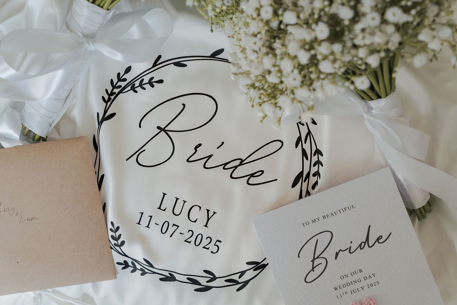 White wedding invitations with floral designs and calligraphy text displayed with delicate baby's breath flowers.
