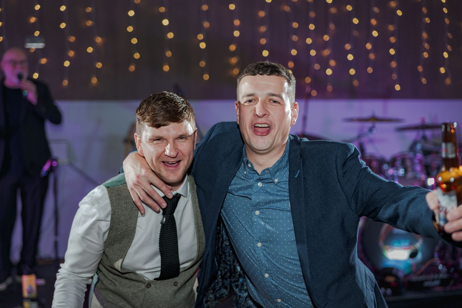 Two people celebrating at a party with string lights twinkling in the background.