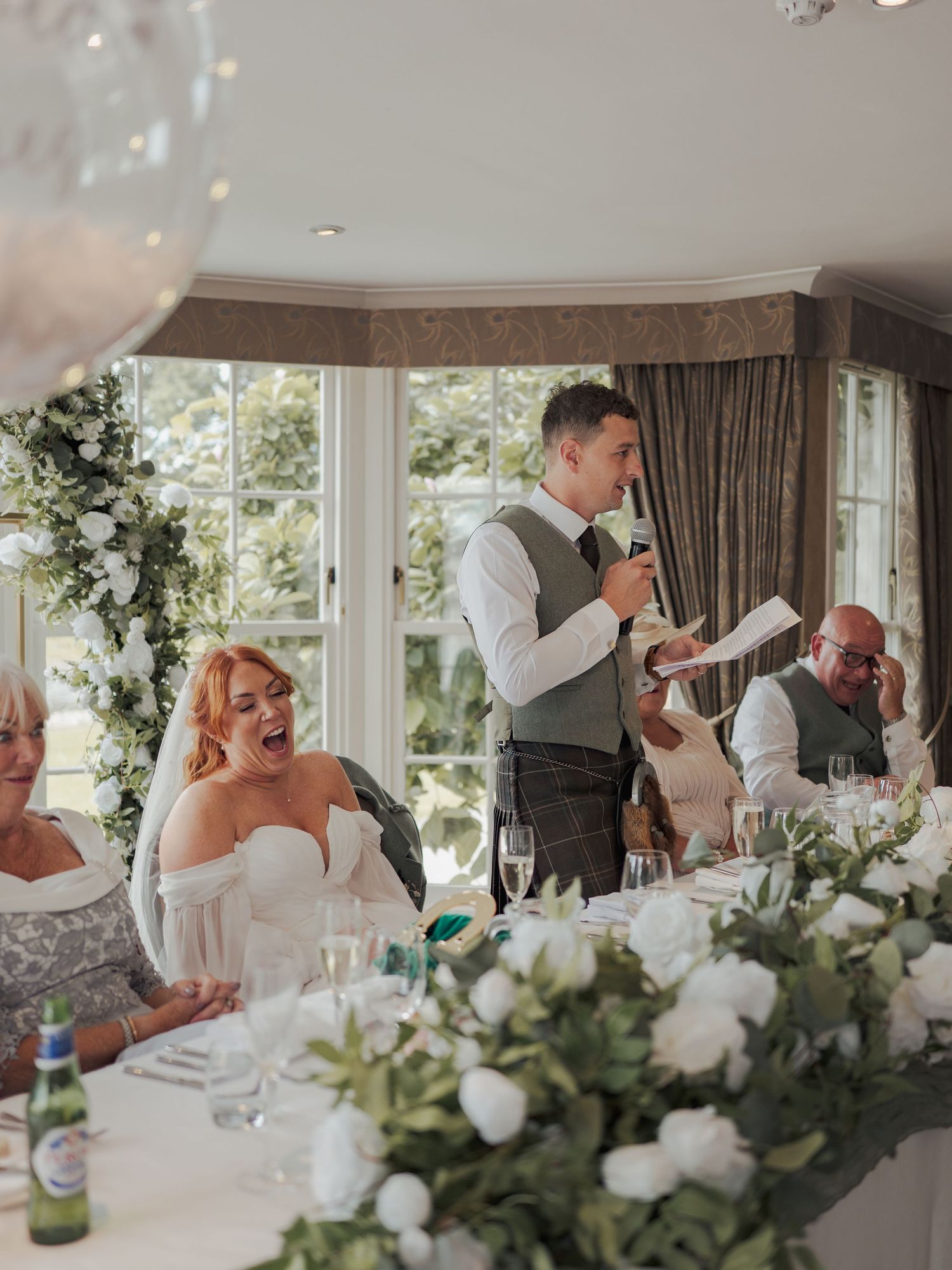 Wedding reception guests seated at decorated tables share laughter and joyful moments during speeches and toasts.