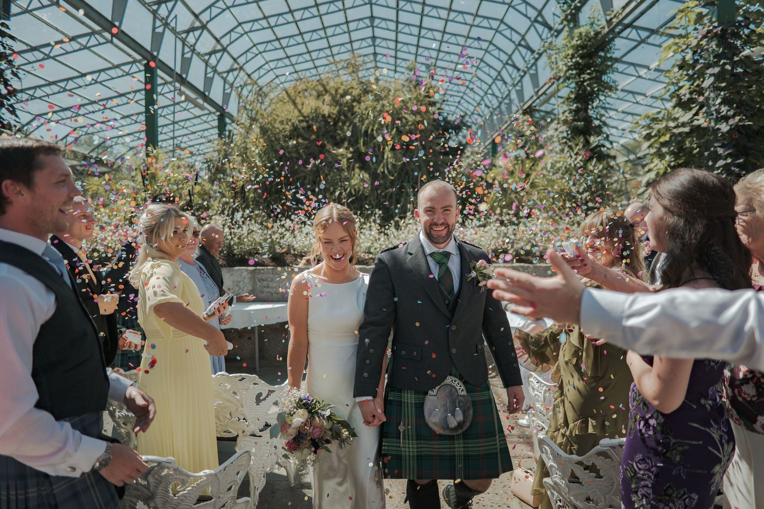 Wedding celebration in David Welsh Winter Gardens in Duthie Park with guests surrounded by lush greenery and natural light.