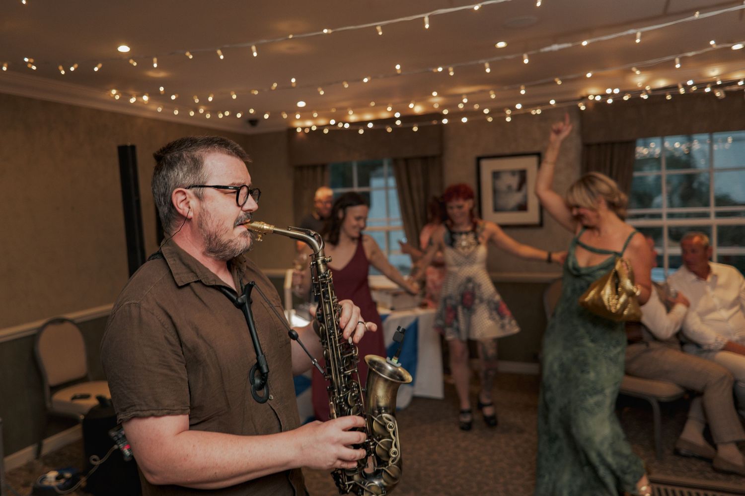 A festive reception venue decorated with warm twinkle lights as guests mingle and celebrate on the dance floor at Banchory Lodge.