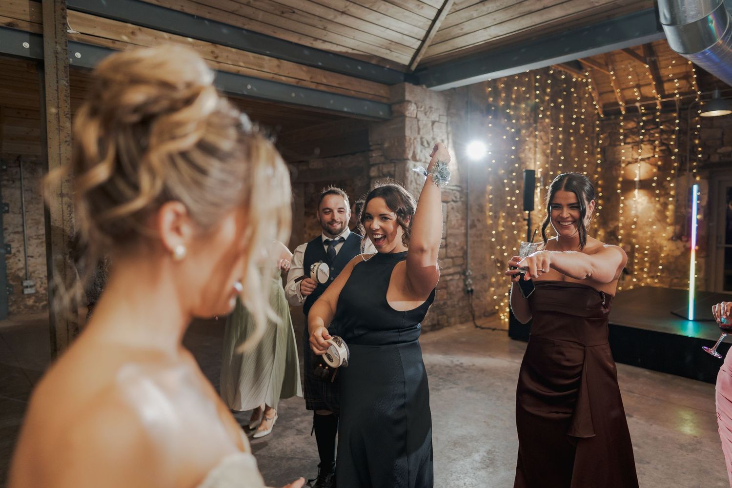 People dancing and celebrating at Falside Mill with twinkle lights creating a warm, festive atmosphere.