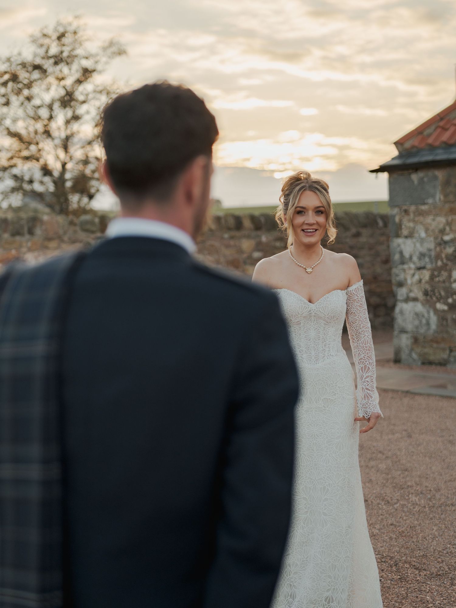 A couple shares a romantic moment at sunset outside Falside Mill during their wedding celebration.
