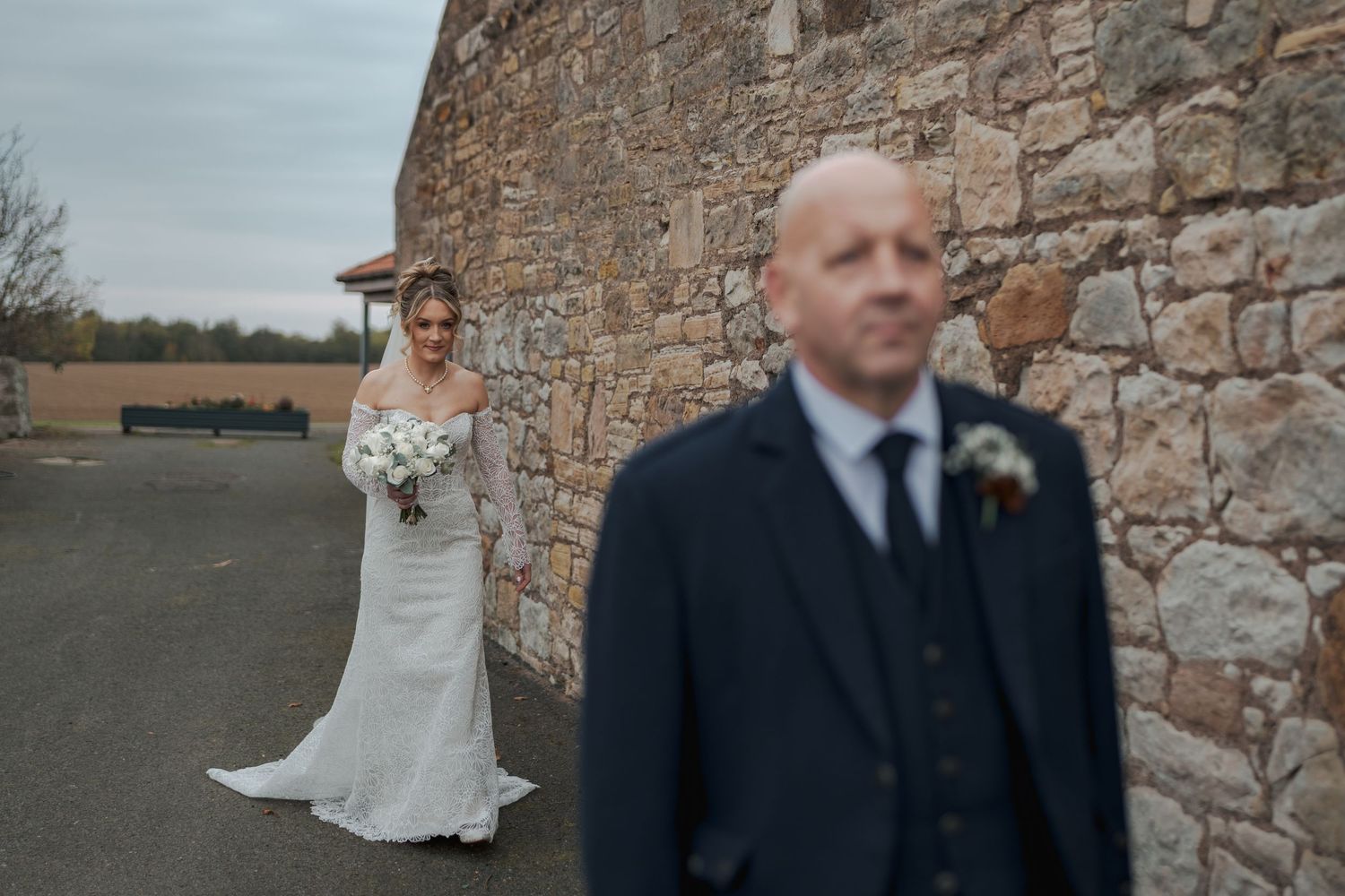 A wedding couple poses against rustic stone walls in a series of romantic outdoor portraits.