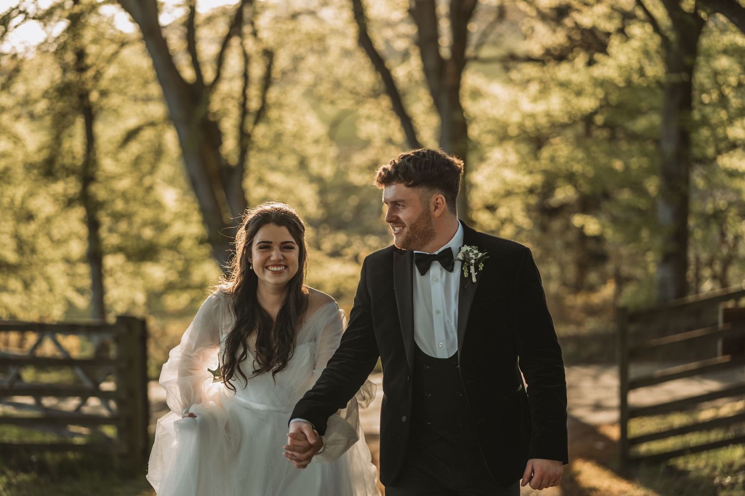 The bride and groom take a sunset stroll through Kinclune Estate, surrounded by autumn trees and wooden fences.