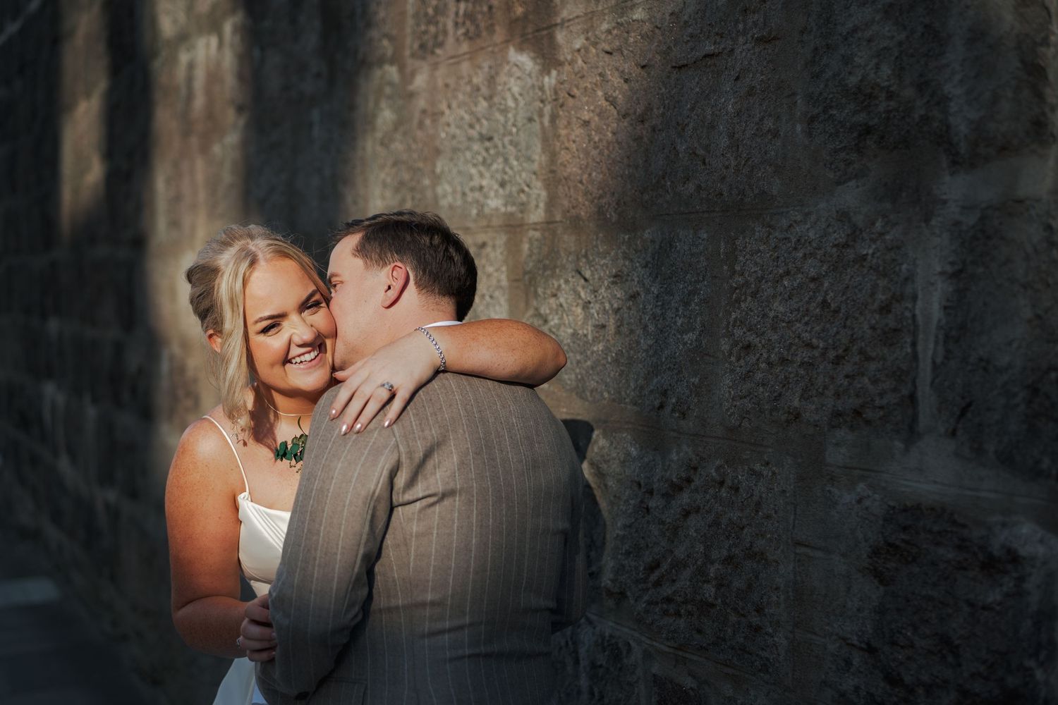 A couple shares an intimate moment during their wedding celebration against a dark textured background.
