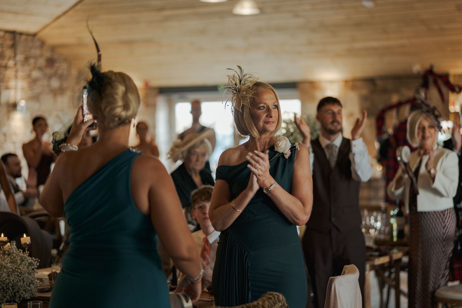 Wedding guests dance and celebrate together on a dimly lit dance floor during a reception celebration.