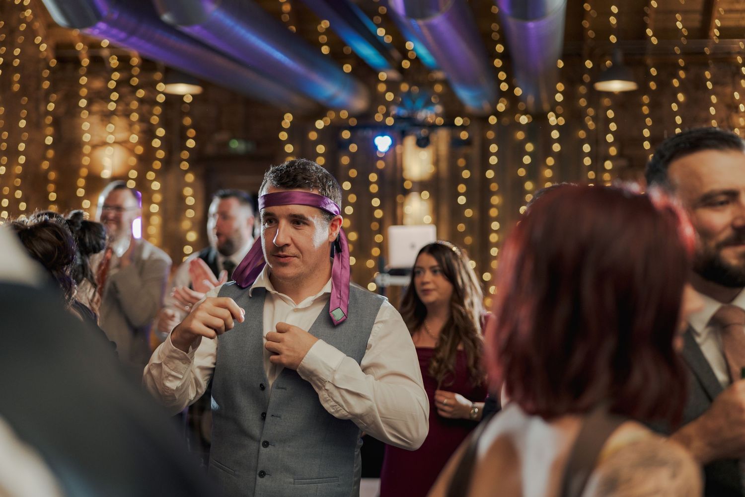 Couples dancing and celebrating on a rustic wooden dance floor at Falside Mill with string lights overhead.