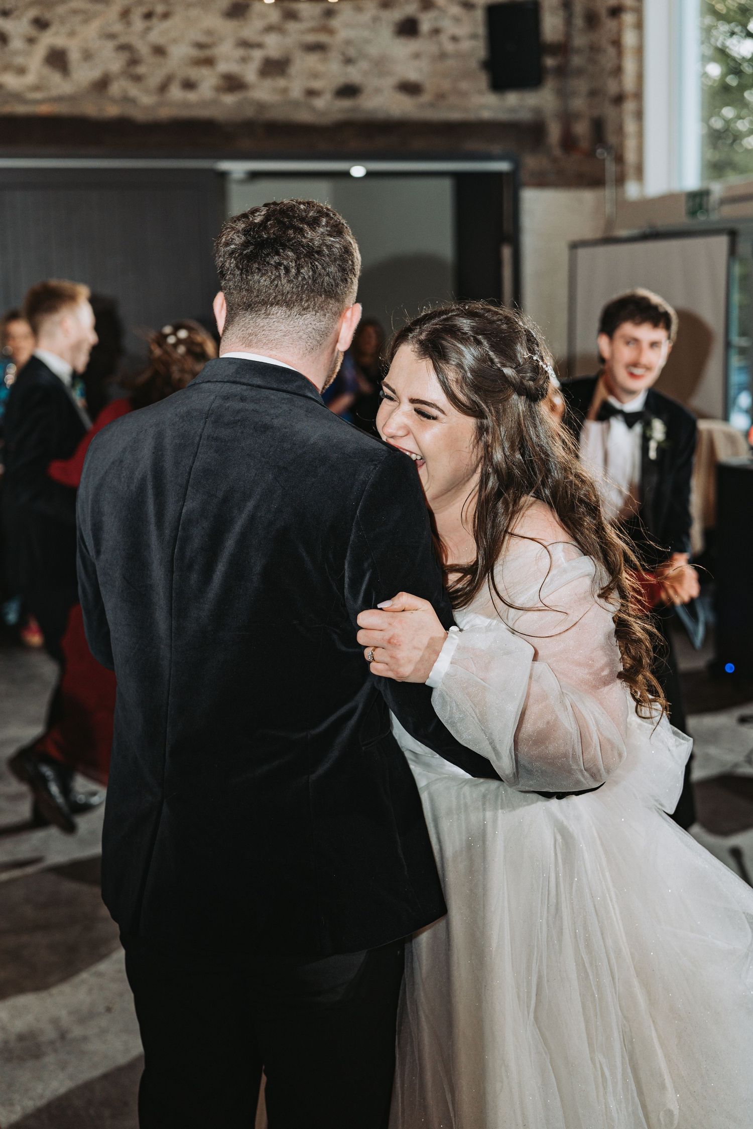 A couple shares a joyful first dance moment during their wedding reception at Kinclune House, with the bride wearing a flowing white gown.