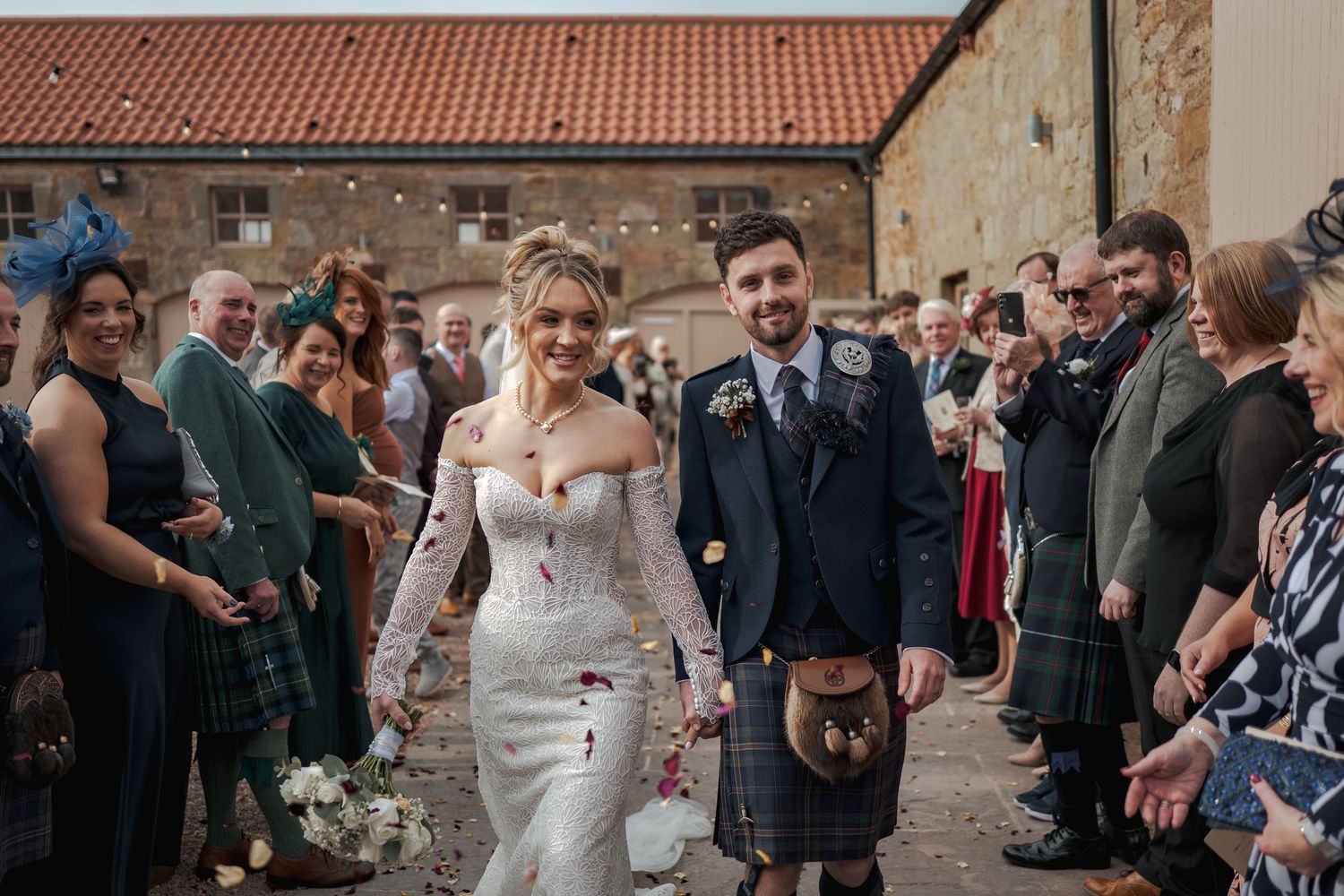 Wedding celebration at Falside Mill with guests in traditional Scottish kilts and formal attire.