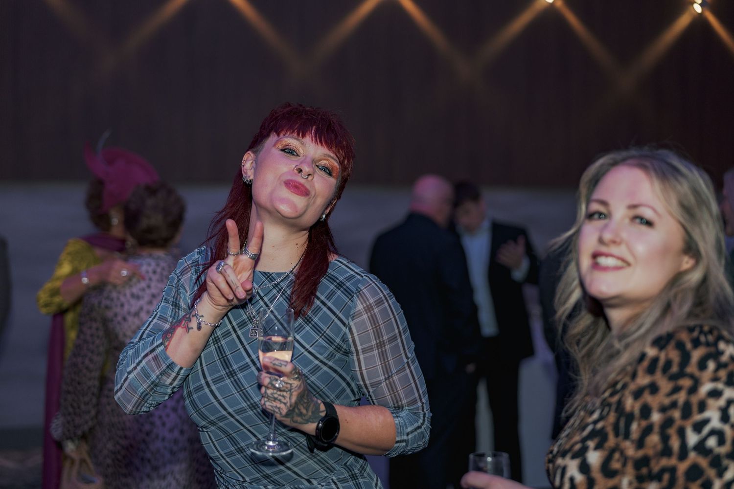 Two friends enjoying drinks and conversation at an evening party with ambient lighting at the Sandman Signature, Aberdeen.