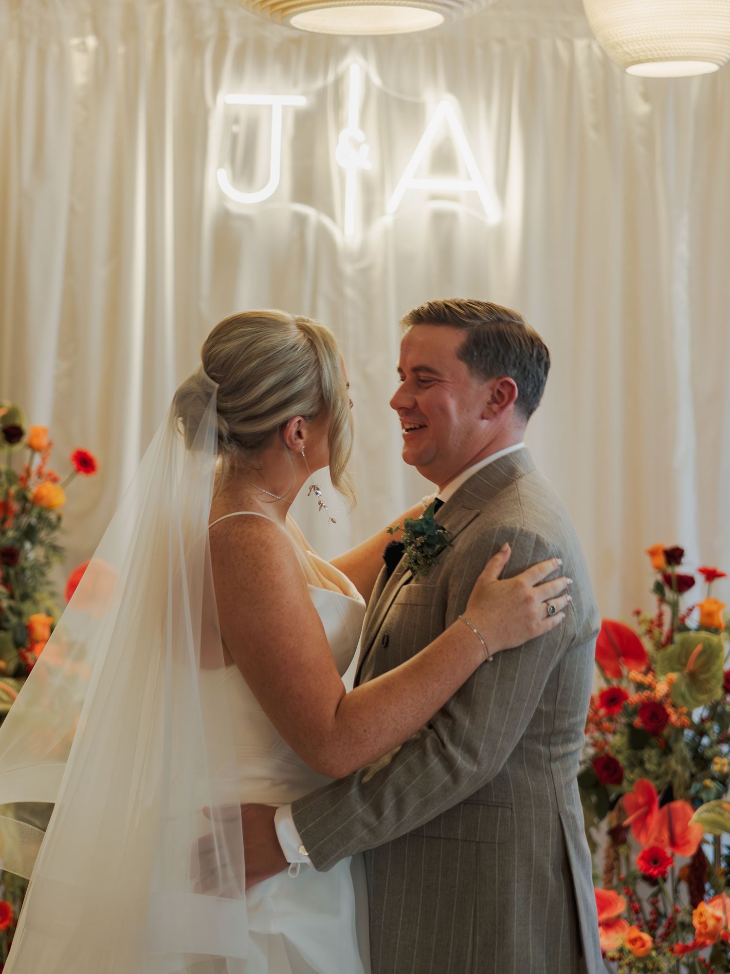 Couple shares emotional first dance at wedding reception with white curtain backdrop.