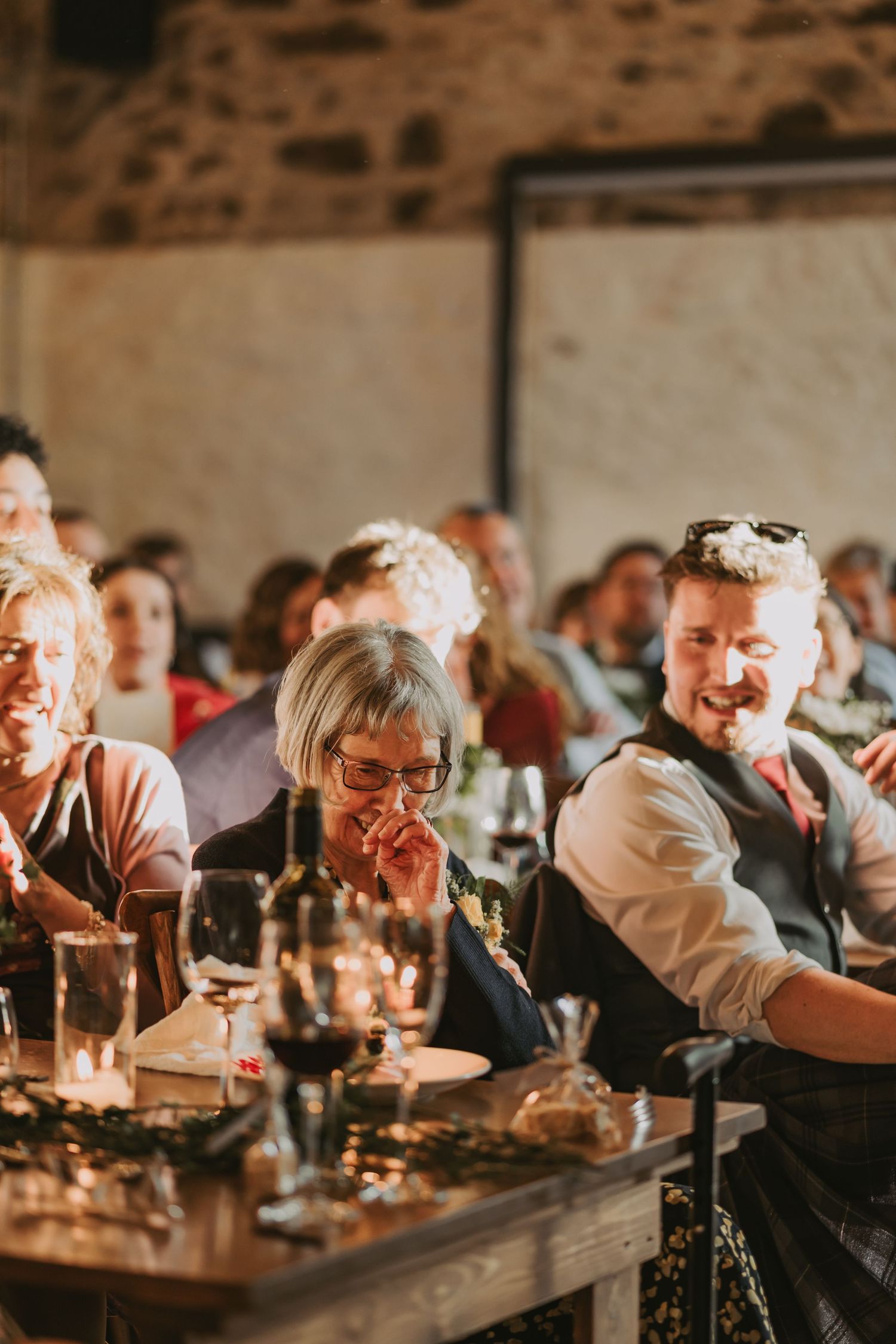 People enjoying a lively dinner gathering with warm candlelight at a rustic wooden table in a casual dining setting at Kinclune House
