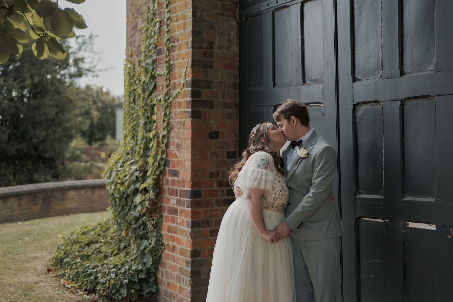 A romantic bride and groom share intimate moments along a brick wall in a series of wedding photos.