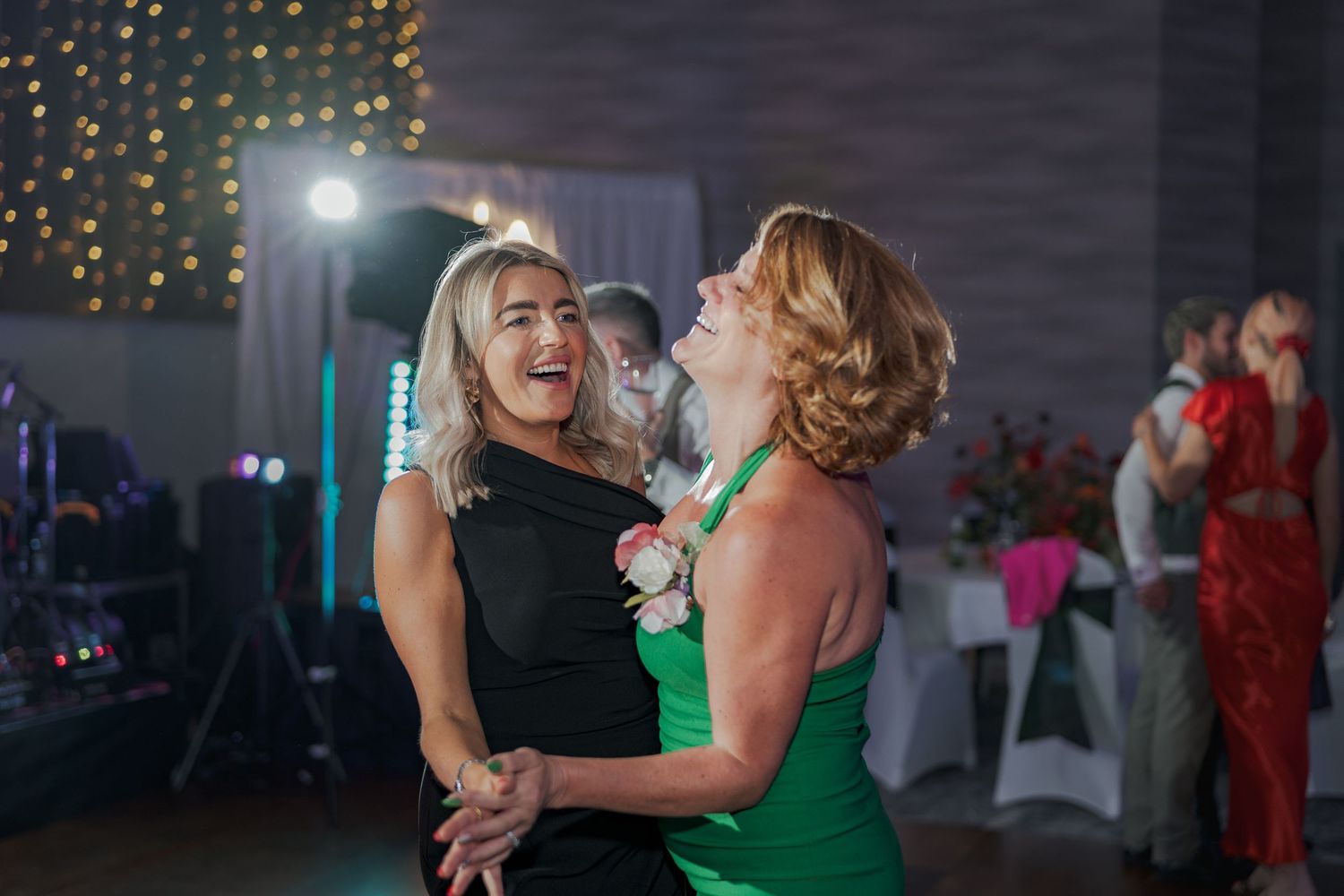 People dancing and celebrating at an evening event with twinkle lights and decorative backdrop at the Sandman Signature, Aberdeen.